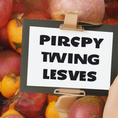 A white and black sign in front of a pile of red apples, with the words "Pirpsy Twing Lesves" written on it.