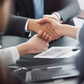 Two people are shaking hands and smiling, showing their friendliness in a professional environment.