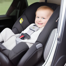 A smiling baby sitting in a car seat, wearing a gray snowsuit.