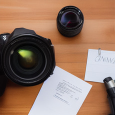 A white piece of paper is sitting on a table next to a pair of camera lenses.