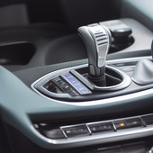 A steering wheel of a car with the car in a parking lot.